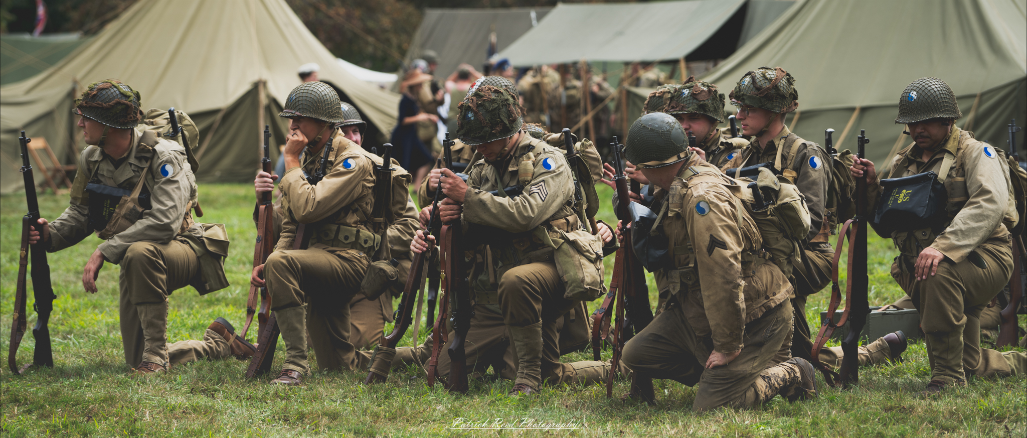 Soldiers kneeling on a parade ground, lined up in orderly rows. Their posture is disciplined and focused, reflecting respect and solemnity during a formal military event or ceremony.